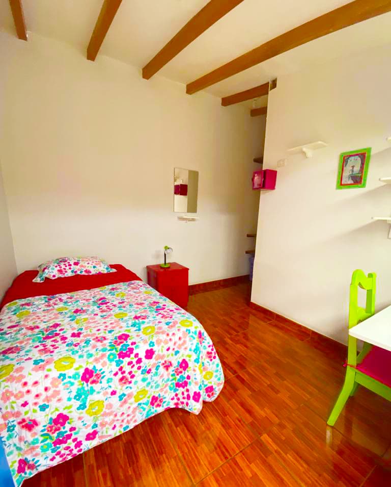 Cozy furnished single room with bed, desk and wooden beam ceiling at Casa Yllika student housing Lima Peru